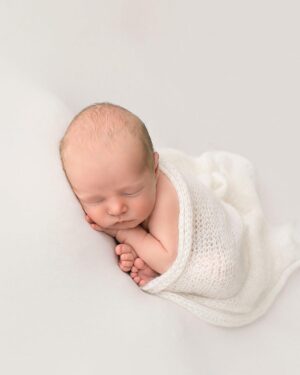 Newborn baby posed on soft cream jersey backdrop Molly during a photo session