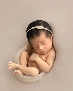 Newborn baby posed on soft tan jersey backdrop Molly during a photo session