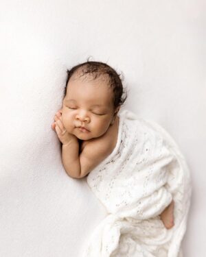 Cream‑coloured textured newborn wrap used as a soft swaddle during baby photo session