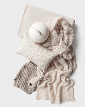 Coordinated newborn photography prop set in oatmeal featuring a stretchy backdrop, pointelle wrap, textured pillow, knitted shorts, tiny headband, and soft teddy bear – full bundle styled for a baby photo session.
